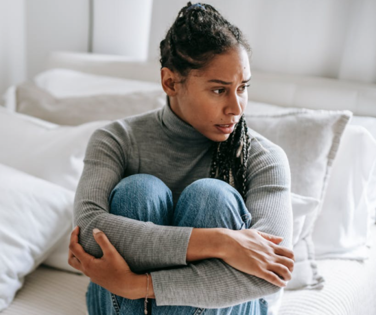 Teen girl sitting with knees up, appearing anxious and reflective